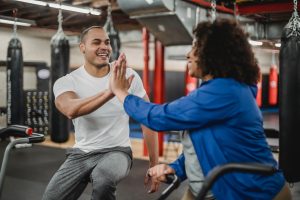 Trainer und Athletin geben sich High-Five vor Fitness-Geräten
