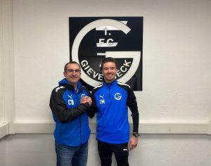 Beim 1. FC Gievenbeck: Co-Trainer Torsten Maas vor Vereins-Logo