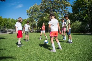 Kinder stehen im Kreis auf Wiese mit Ball