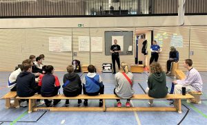Sporthelferinnen und Sporthelfer auf Bank in Turnhalle