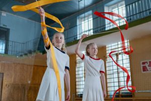 Rhythmische Sportgymnastik: zwei Turnerinnen mit Band in der Turnhalle